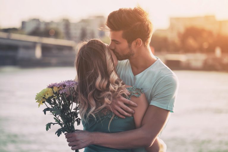 man giving flowers to his girlfriend in front of water