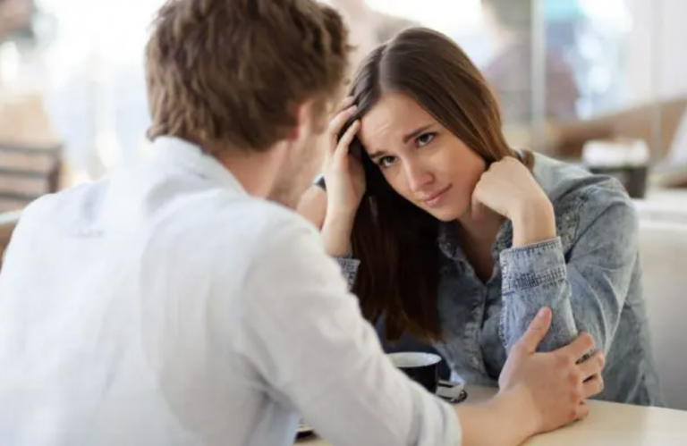 woman looking worriedly at man sitting across from her.