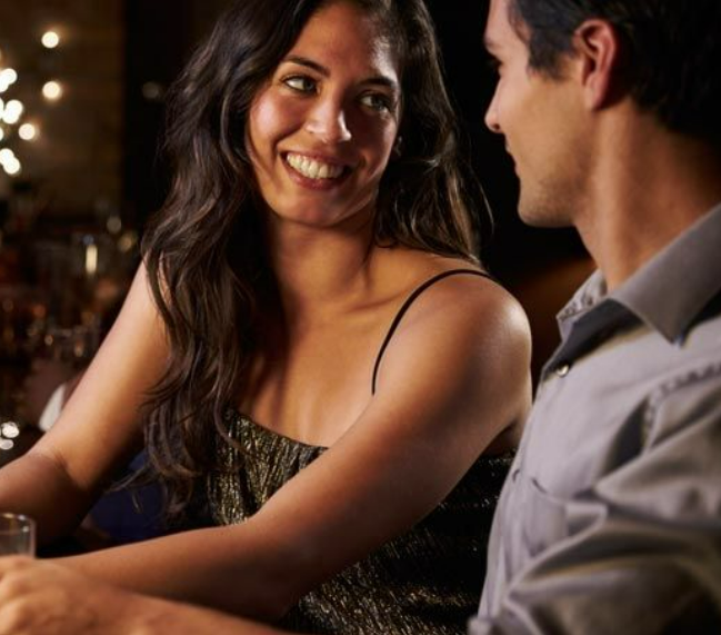 woman looking at man smiling happily on a first date