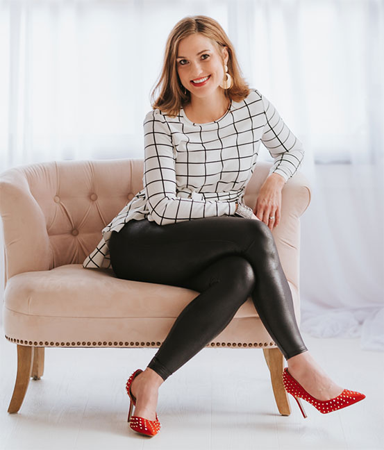 Professional photo of a woman sitting on a chair with her legs crossed.