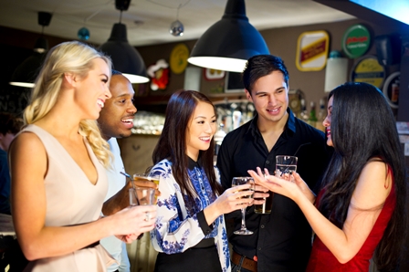 A group of three women and two men sharing a drink at a bar.