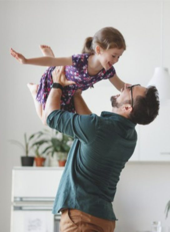 Dad holding his daughter up affectionately & laughing.