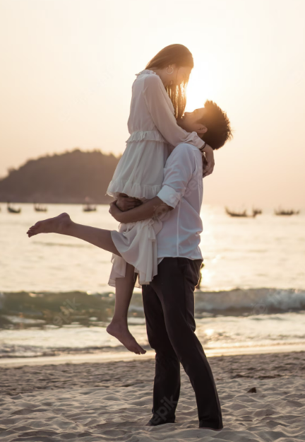 boyfriend holding his girlfriend lovingly at the beach with the sunset in the background.