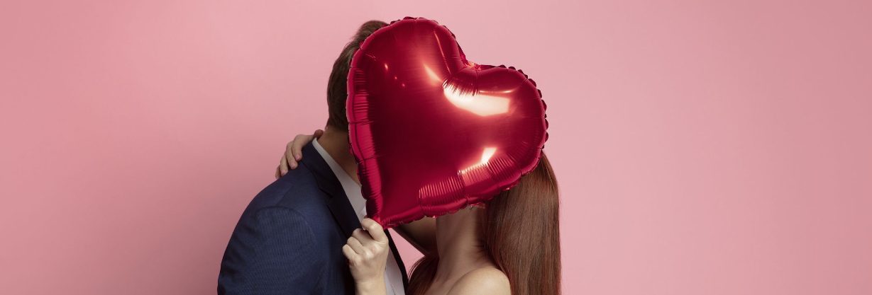 Couple holding heart-shaped balloons.