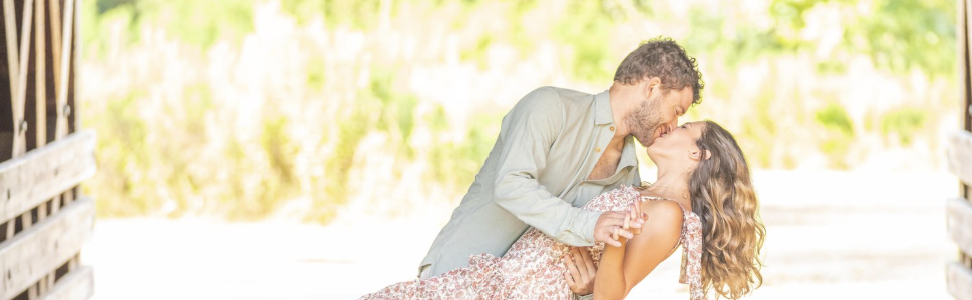 man holding girlfriend in a dip position while kissing her.