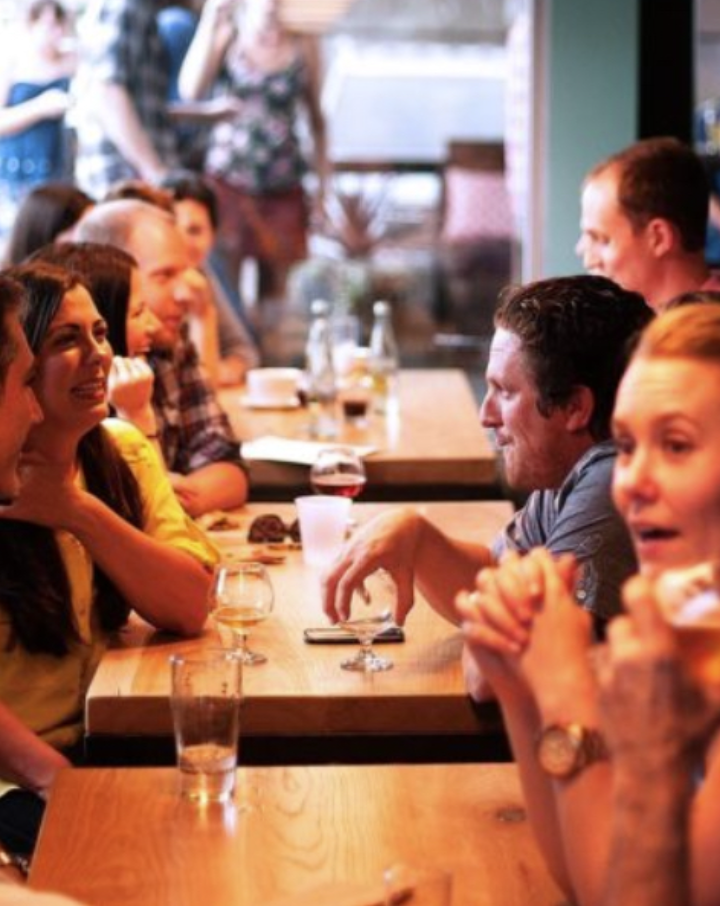 group of single men and women laughing and talking with each other at a speed dating event.