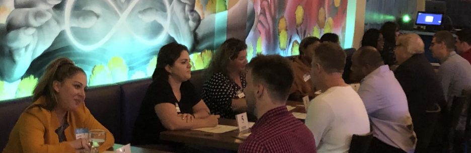 group of single men and women sitting across from each other at a speed dating event.