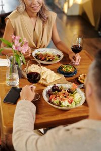 Couple on a date at a restaurant. The man and woman are both holding a glass of red wine. 