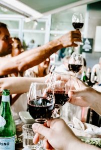 Group of people at dinner cheersing with glasses of red wine.