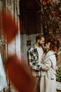 Couple embracing each other under fall leaves.